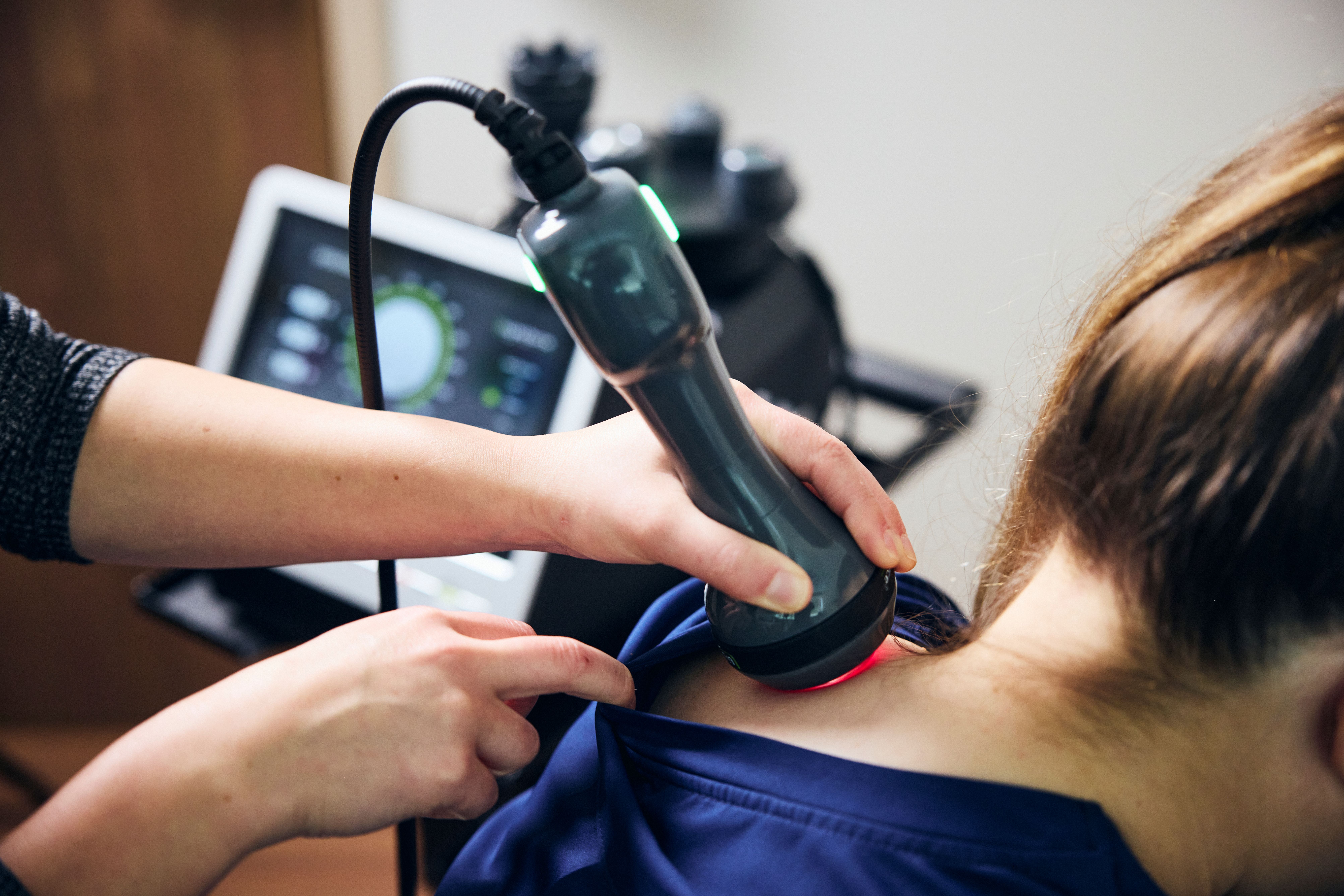 A laser device is being placed on the back of a patient's neck. 